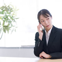 遠くを見ながら通話する新入社員、スマートフォンで会話中の写真