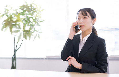 深刻な表情でスマホで通話するスーツ姿の女性