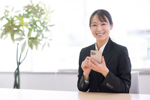 笑顔でスマホを持つスーツ姿の女性