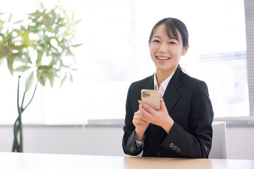 スマートフォン操作を指導する笑顔の女性社員