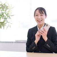 スマホを片手に笑顔の女子社員、受け取ったメッセージに喜ぶの写真