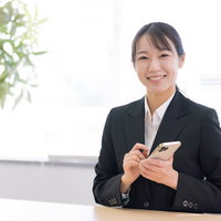 スマートフォンを操作する笑顔のショップ店員の写真