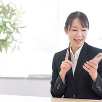 スマートフォンの操作を案内する笑顔の女性の写真