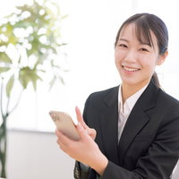 笑顔でスマホ操作を教えてくれる女性会社員の写真