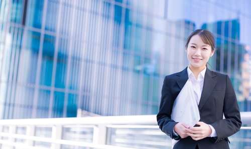 ファイルを持ってオフィスへ向かう笑顔の女性