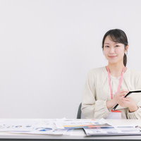 タブレットを持ちながらデスクでメモを取る女性の写真