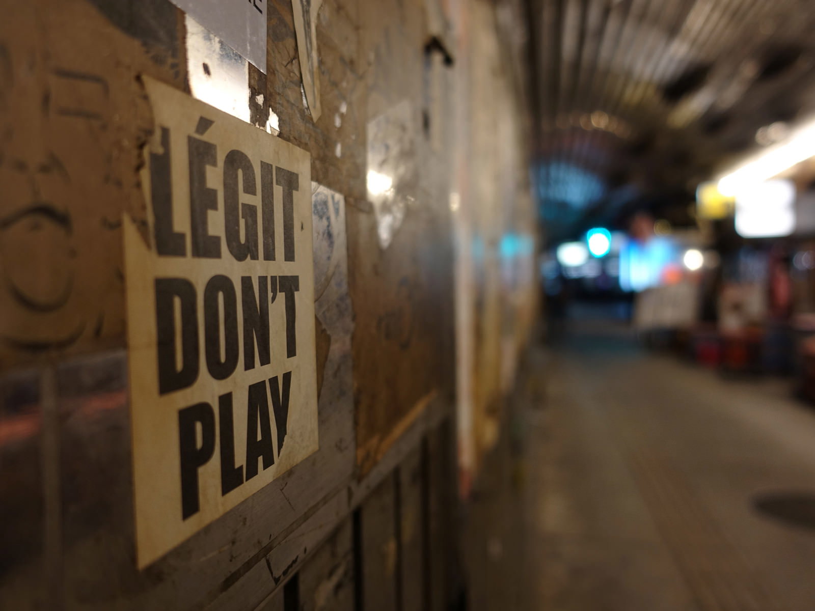 コンクリートの壁に貼られた「LEGIT DON'T PLAY」と書かれたチラシ