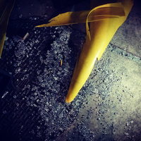 殺風景な路地裏に置かれた黄色いカラーコーンと破壊されたアスファルトの写真