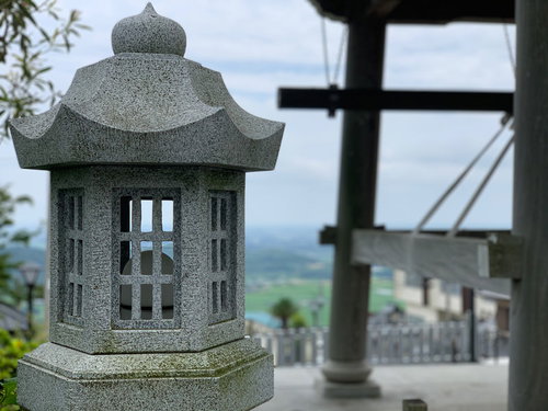 神社の境内に立つ石灯籠と社殿の風景
