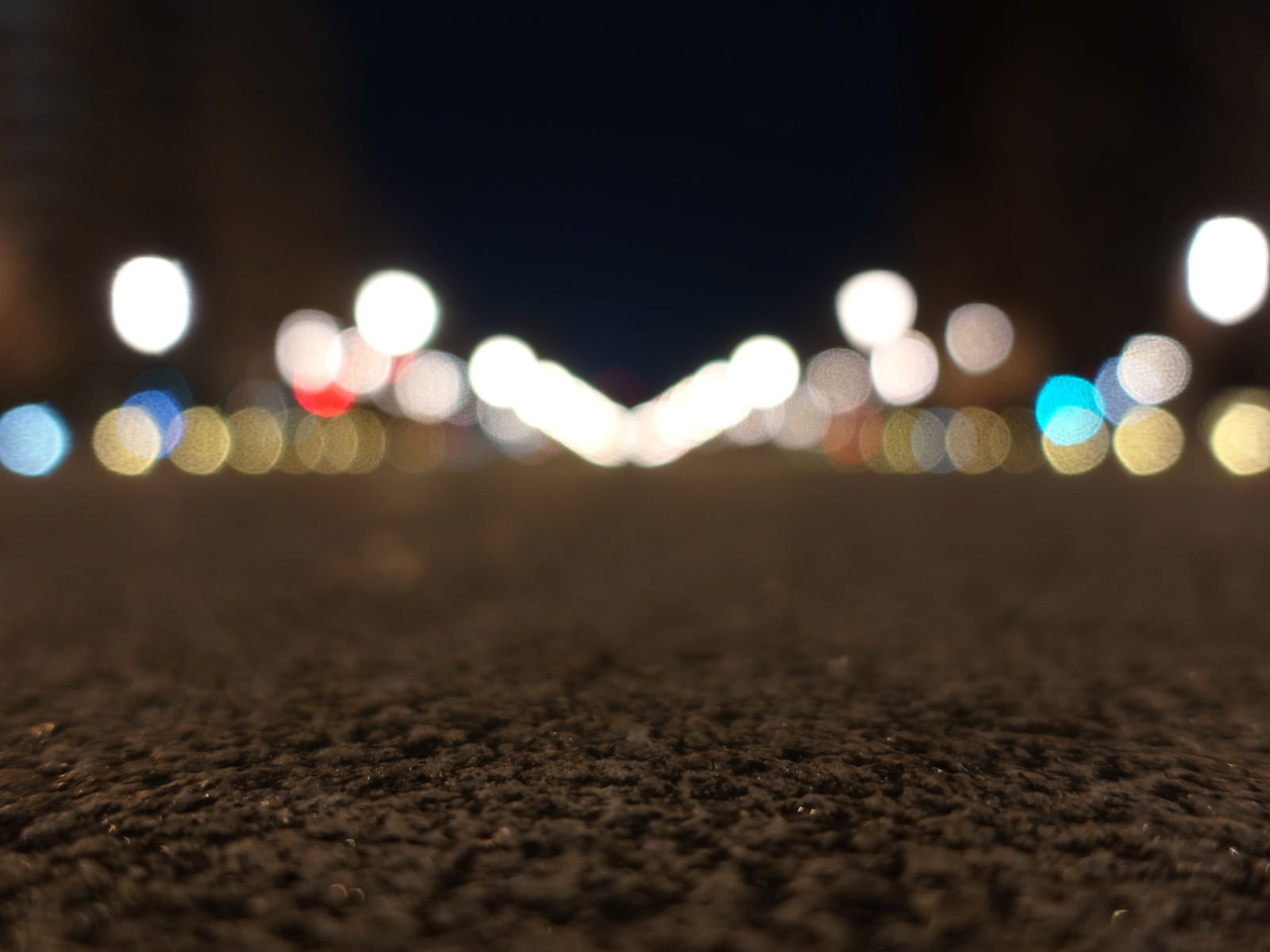 夜の石畳の上にボケた街灯の光が温かく広がる風景