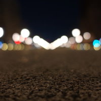 夜の石畳に映るボケた街灯の光と地面の温かみの写真