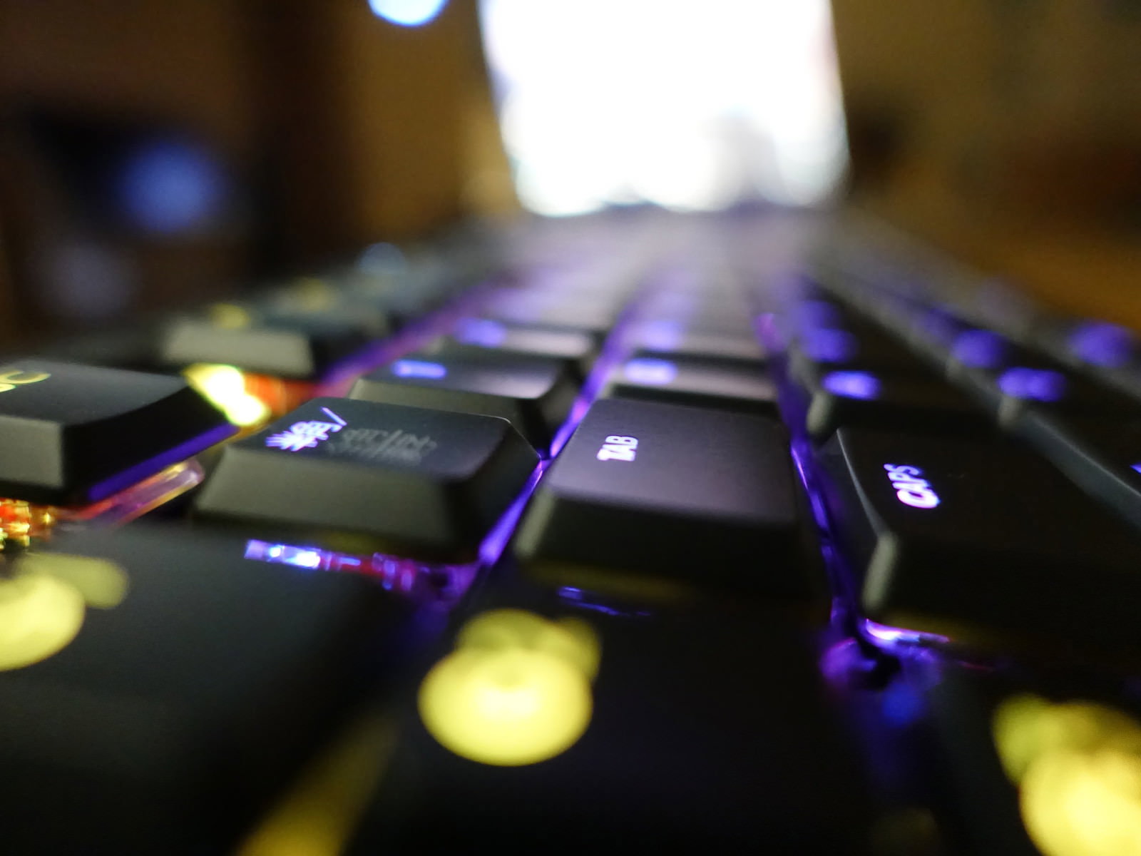 LEDバックライトが紫や青に光るゲーミングキーボードのクローズアップ