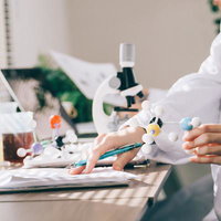 研究室で論文を書きながら分子構造模型を持つ実験の写真