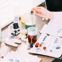 研究室の机の上でレポートを確認しながら実験液を調べる研究者の写真