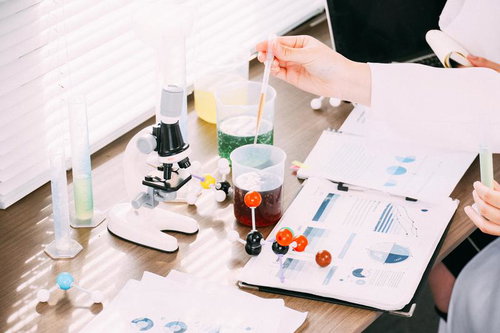 研究室の机の上でレポートを確認しながら実験液を調べる研究者