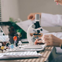 顕微鏡を使って標本を観察する研究者の研究室風景の写真