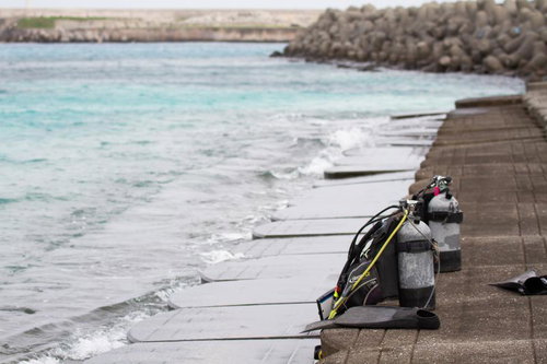 防波堤のある海岸でダイビングタンクとホースが置かれた光景の写真