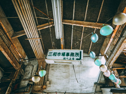 今でも落ちてきそうな三和市場事務局の案内看板