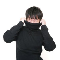 黒いタートルネックを被って嫌がる男性の写真