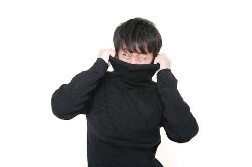 黒いタートルネックを被って嫌がる男性