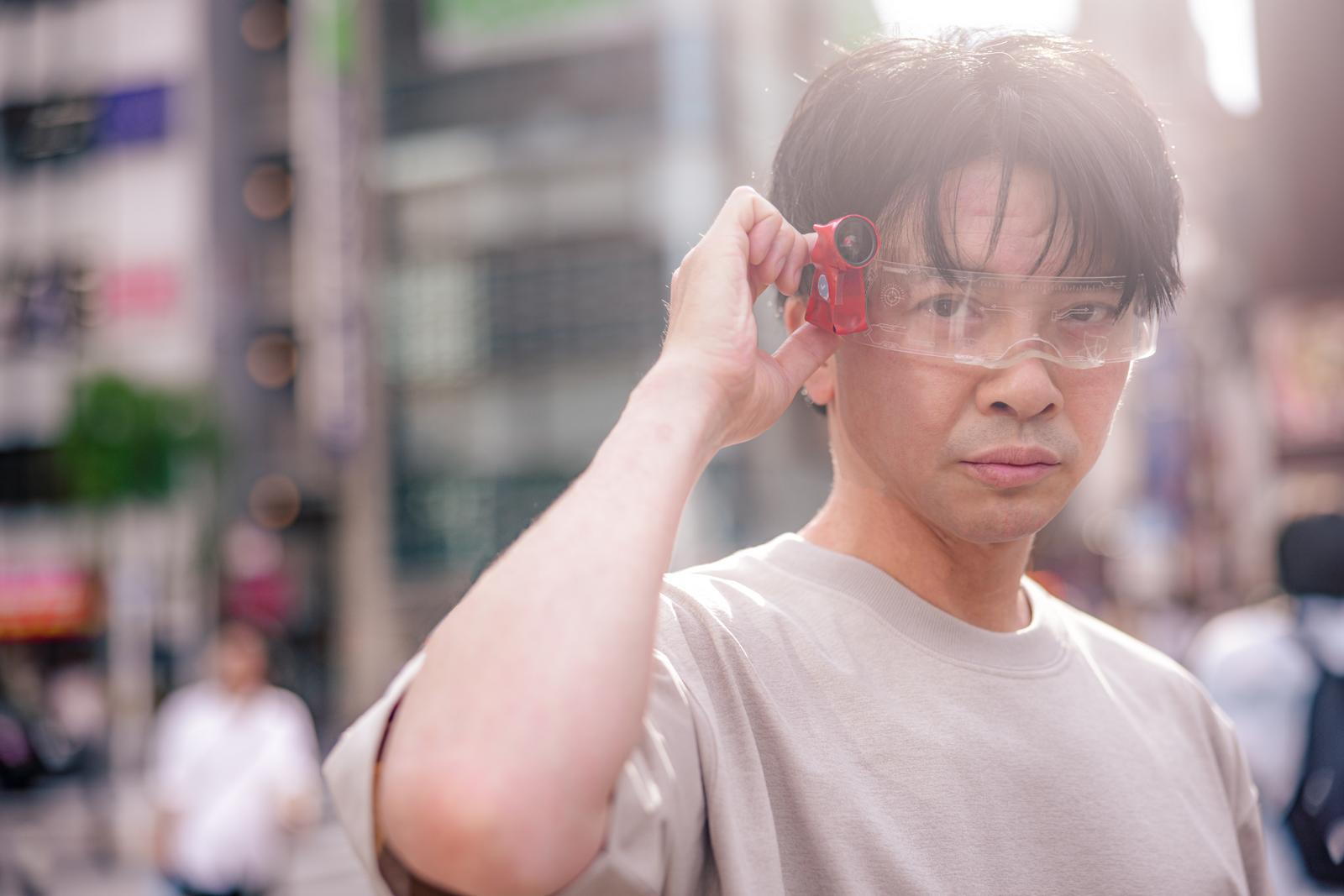赤いARグラスを装着して眼鏡を調整する男性［モデル：金子周平］