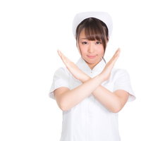 拒否のポーズを取る白衣のナース、バツ印に腕を交差させた看護師の写真
