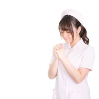 お願いナース〜ピンクのナース服姿で祈る女性の写真