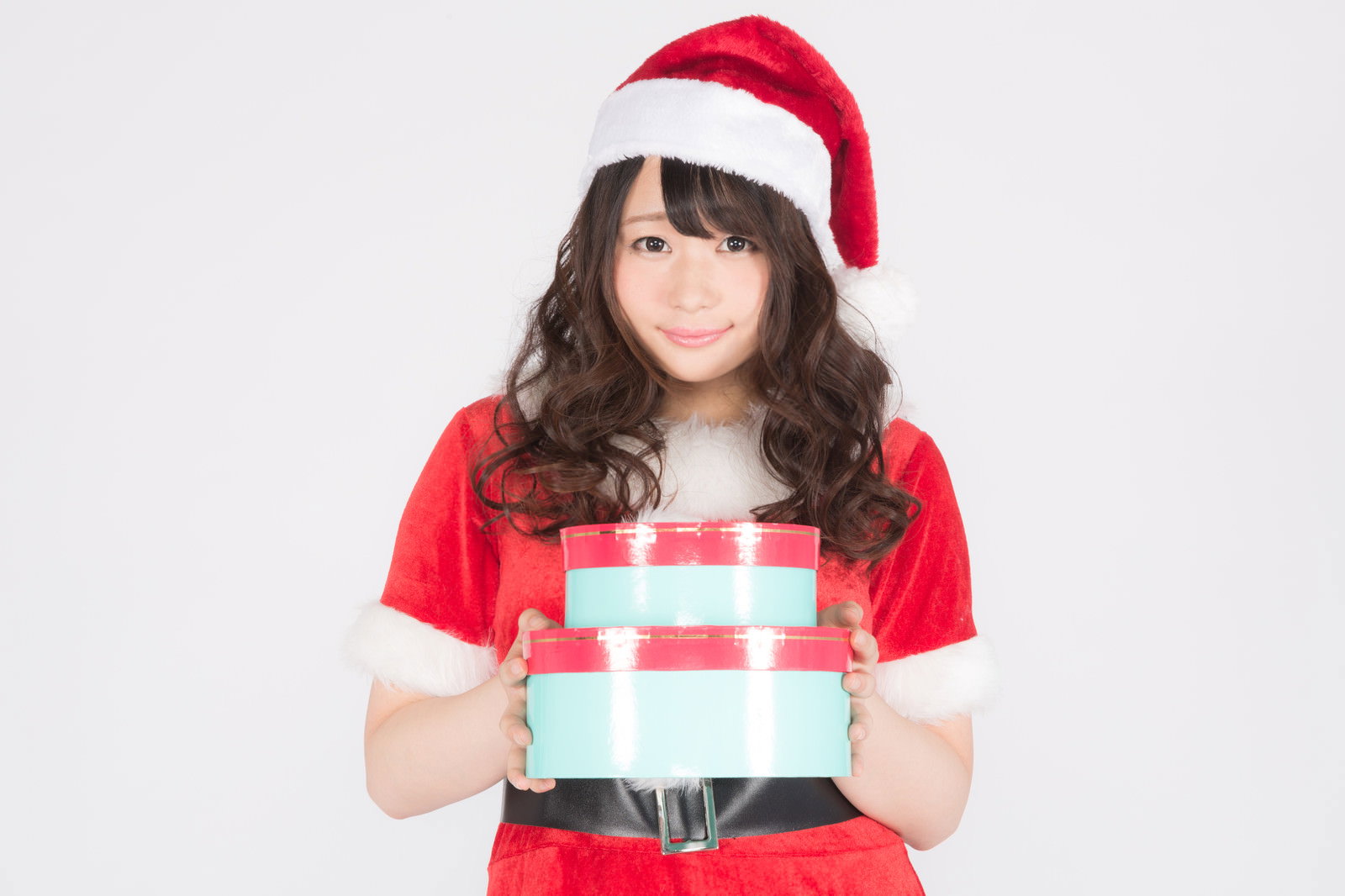サンタクロースのコスプレをした女性が白いプレゼント箱を持っている［モデル：茜さや］