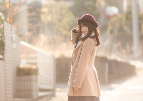 コートを着た女性の見返り美人、秋の夕暮れに振り返る