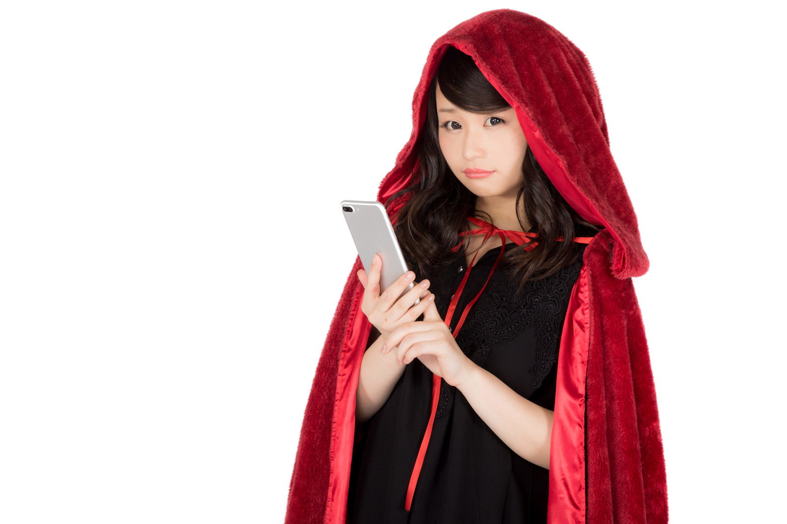 赤いフード付きマントを着てスマートフォンを持つ女性［モデル：茜さや］