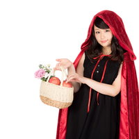 赤ずきんの仮装をした女性がバケットの林檎を持つの写真