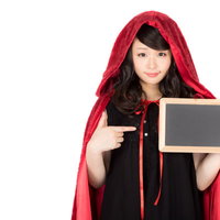 ハロウィン仮装のお知らせ案内を持つ赤ずきん女性の写真