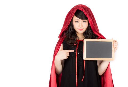 ハロウィン仮装のお知らせ案内を持つ赤ずきん女性