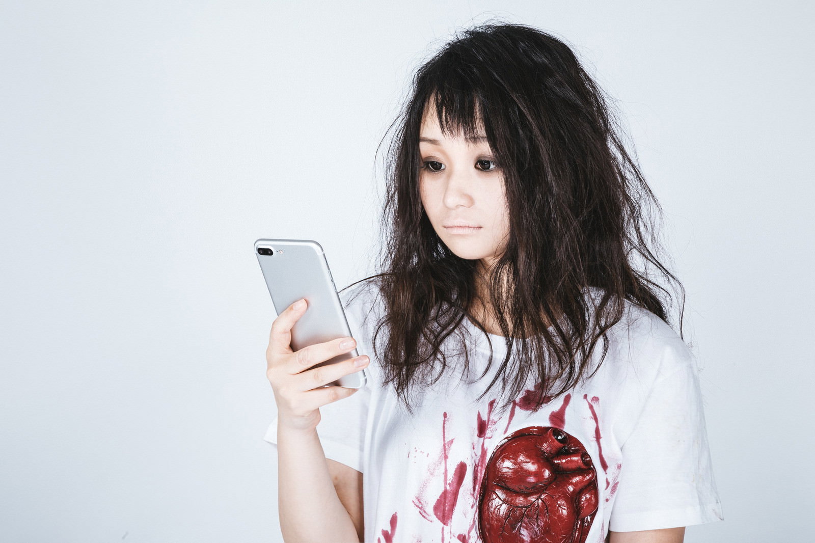 ホラー系Tシャツを着た女性がスマホを見ている［モデル：茜さや］