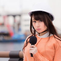 被災地からのニュース中継で安全ヘルメットを着用するアナウンサーの写真