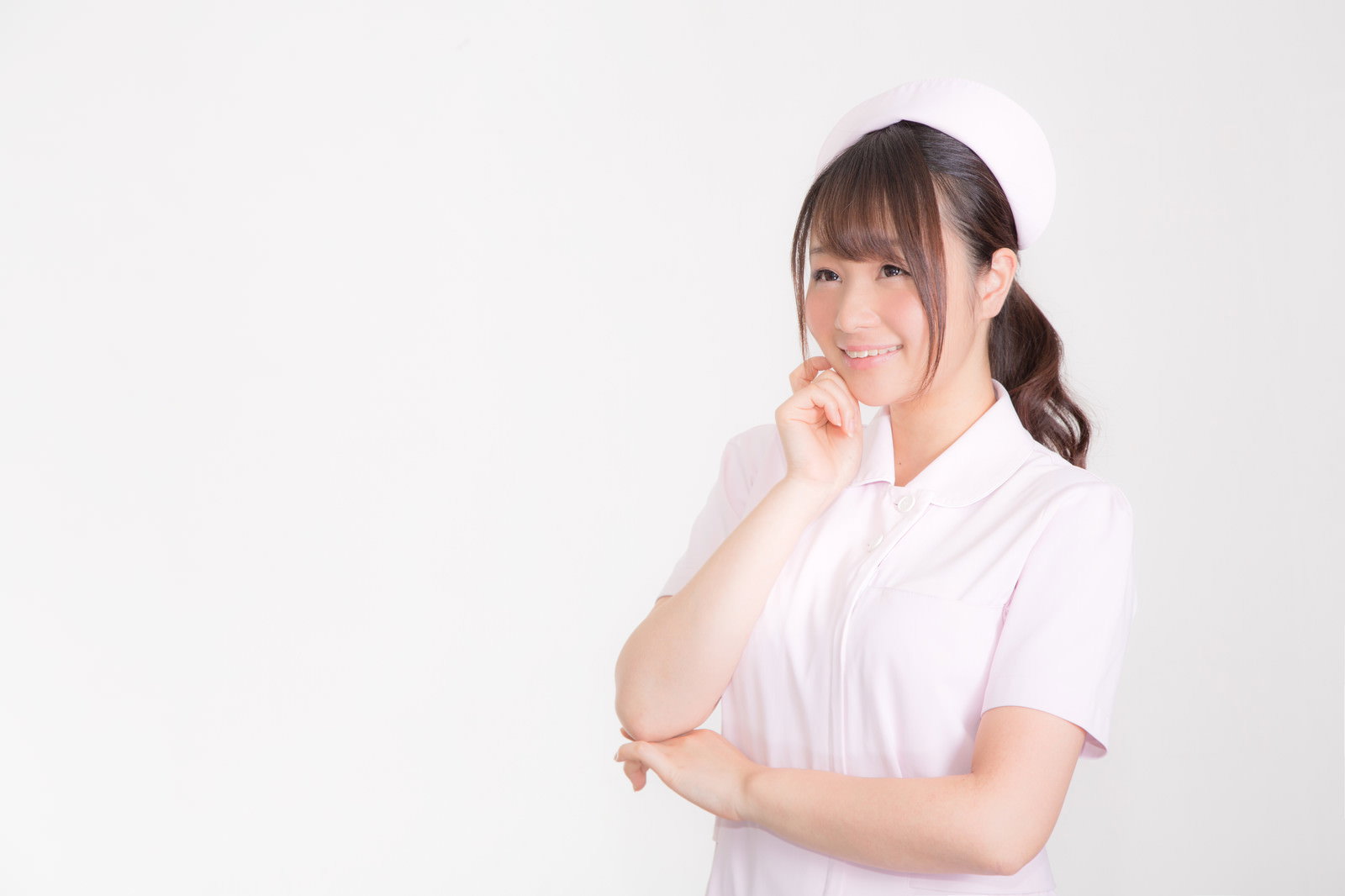ピンクのナースキャップをかぶり微笑む白衣の女性［モデル：茜さや］