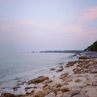 薄紫とピンク色に染まる朝焼けの沖縄海岸線の写真