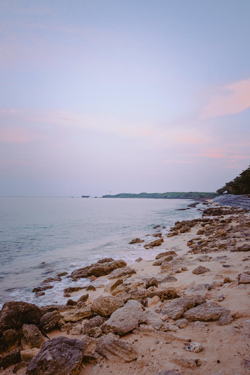 薄紫とピンクの朝焼けが美しい沖縄の海岸線