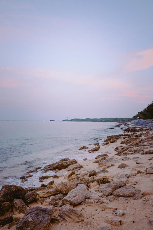 薄紫とピンク色に染まる朝焼けの沖縄海岸線