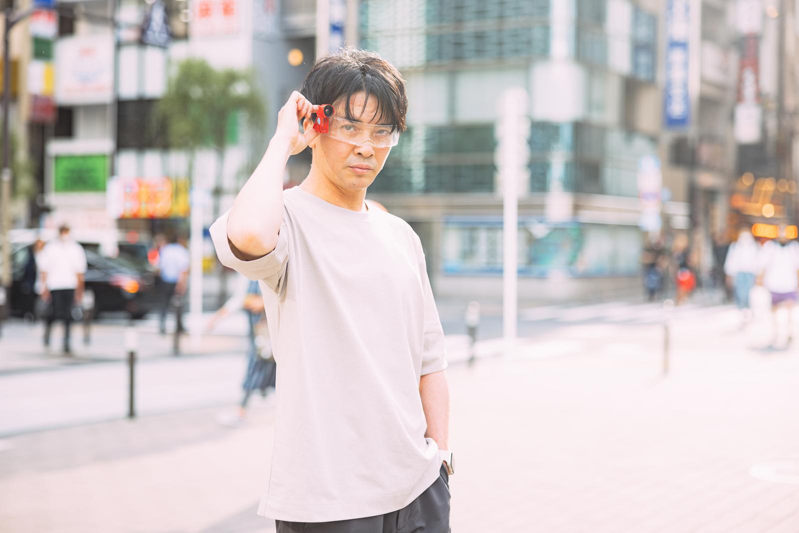 都市の広場でARグラスを装着して正面を見つめる男性［モデル：金子周平］
