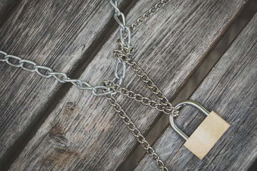 二種類の鎖と南京錠でロックされた木製の板のセキュリティ