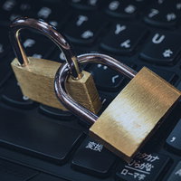 黒いキーボードの上に置かれた金色の南京錠で表現するセキュリティ対策の写真