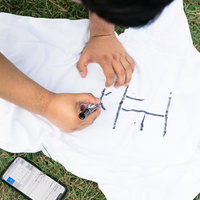 白いTシャツに正義の文字をペンで書き込む男性の写真