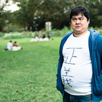 公園の芝生をうろつく正義マン - 青いカーディガンの男性キャラクターの写真