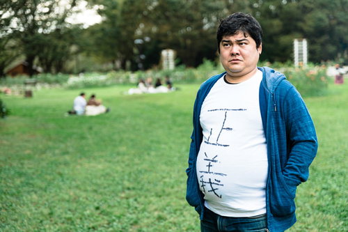 公園の芝生をうろつく正義マン - 青いカーディガンの男性キャラクター