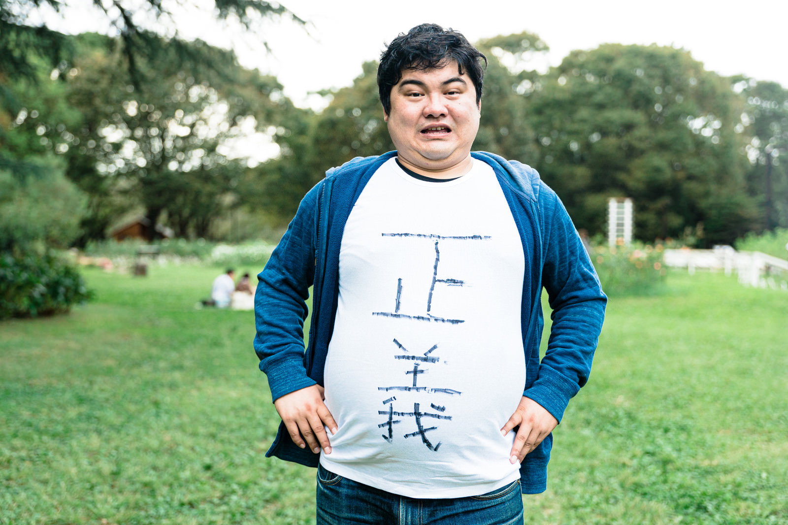 青と白のラグランシャツを着てお腹を突き出すメタボな男性［モデル：段田隼人］