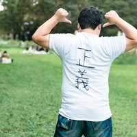 背中の「正義」を見せつける勝者のポーズ｜公園で力こぶを作る男性の写真