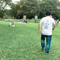 公園を見回る正義マン、芝生の上を歩く男性の後ろ姿の写真