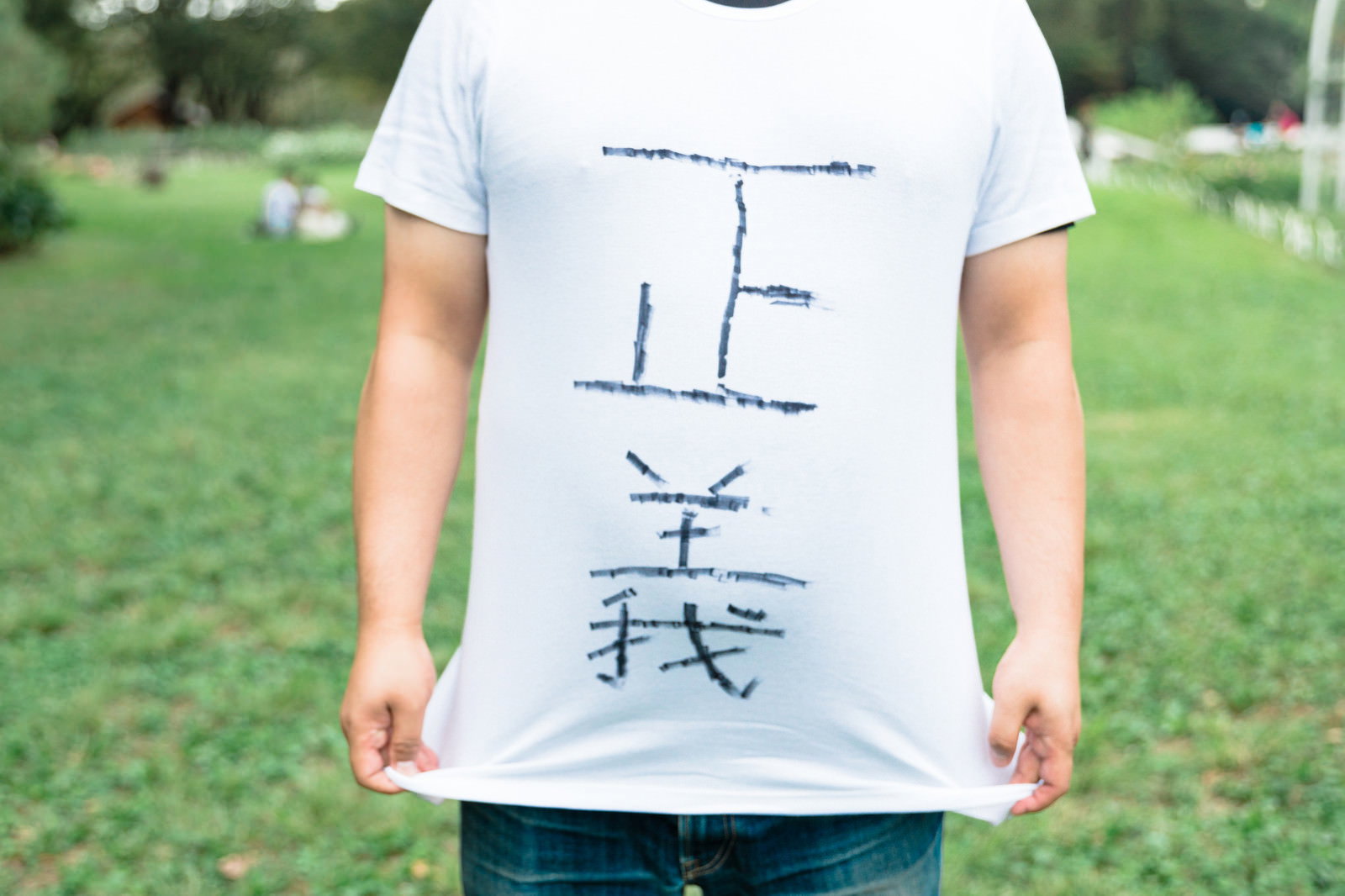胸元に「正義」と縦書きで書かれた白いTシャツを着た人［モデル：段田隼人］