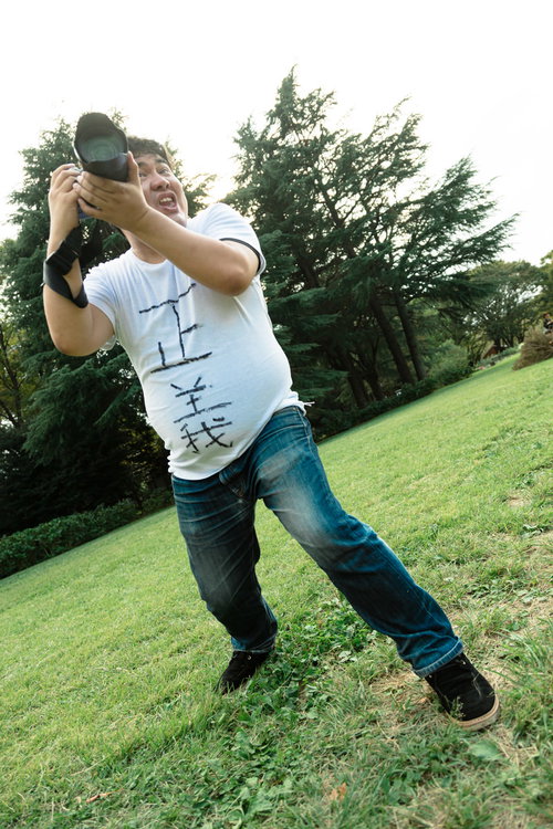 撮影している俺かっこいいマン、一眼カメラで芝生の上で撮影中